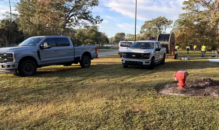 Cardinali Communications crew and trucks on a job site with a fiber cable reel